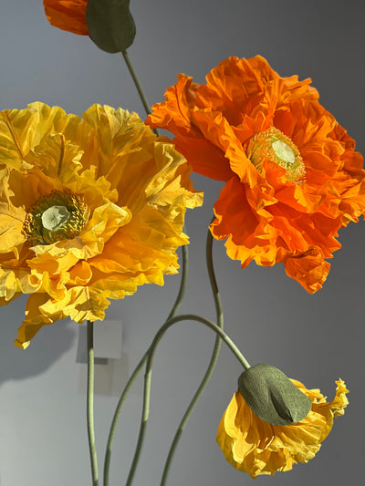 Breathtaking orange and yellow paper flowers on sleek metal stands, perfect for weddings