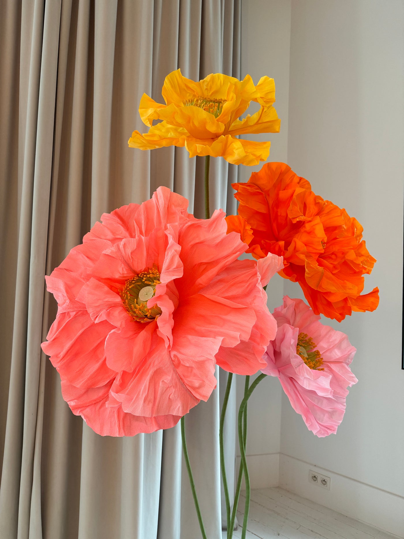 Customizable giant paper flower displays in orange and hot pink for window installations