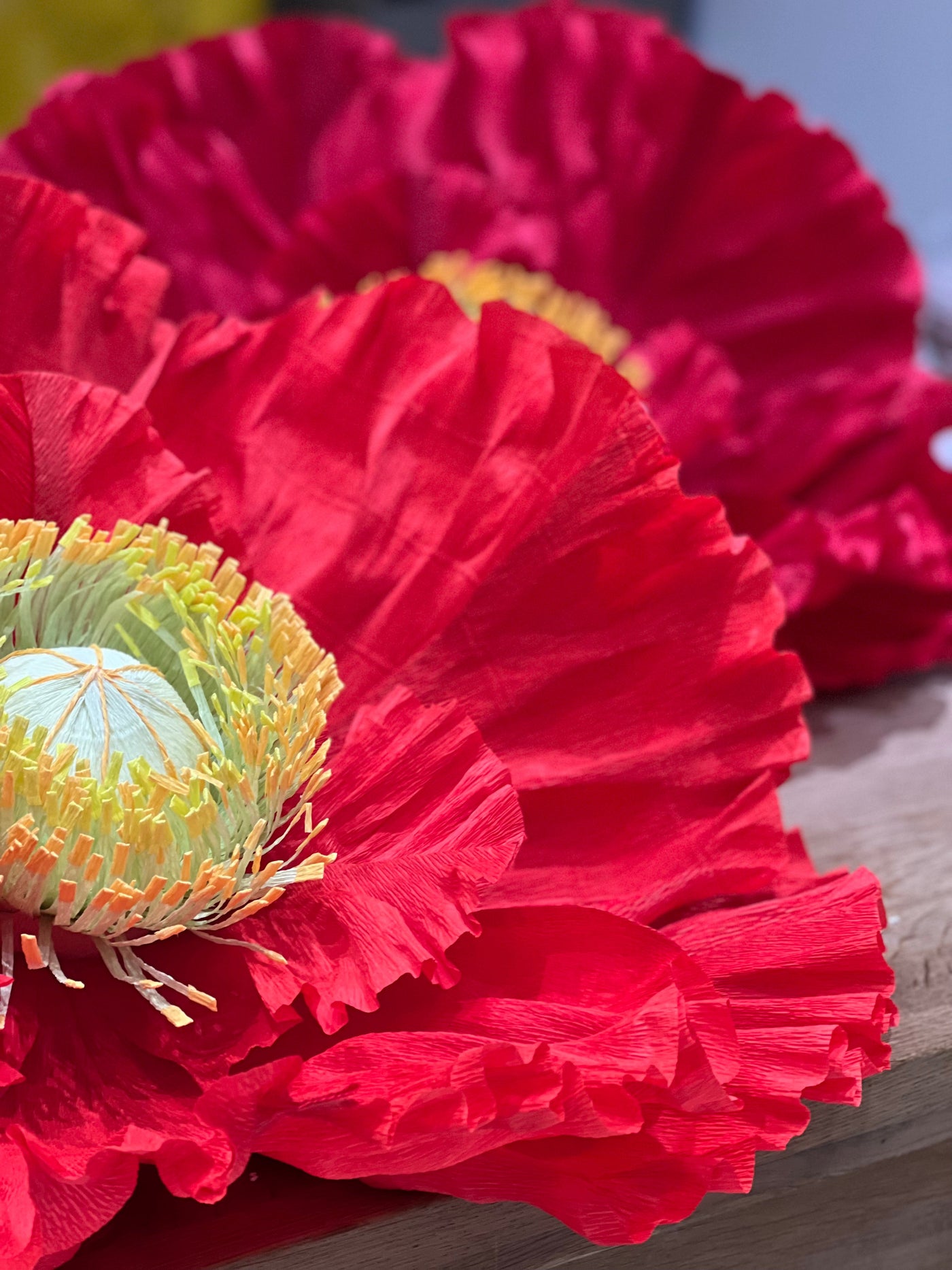  Vibrant, giant free-standing paper poppies in red, orange, and yellow hues. The intricate details of the paper petals and black centers create a striking visual display.